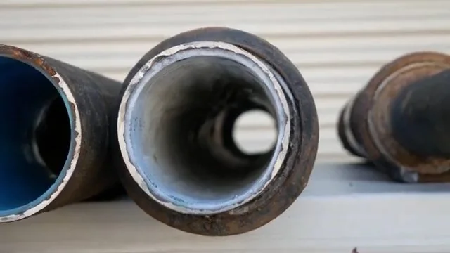 Cut sections of dark pipe with a bright liner inside, resting on a white surface.